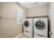 A laundry room with a front-load washer and dryer, a shelf, and a window with shutters at 7949 E Boise St, Mesa, AZ 85207