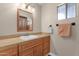Bathroom featuring a vanity with tan tile countertop, mirror, and a window for natural light at 915 S Saranac Ave, Mesa, AZ 85208