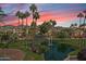 Scenic view of the community featuring a pond, fountain, palm trees, and mountain views under a colorful sunset sky at 9708 E Via Linda -- # 2328, Scottsdale, AZ 85258