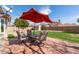 Backyard patio with umbrella, a table with chairs, and green grass at 11445 S 44Th St, Phoenix, AZ 85044