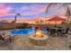 Inviting backyard with a stone fire pit, a pristine pool with a waterfall, and comfortable seating, perfect for outdoor relaxation at 11965 W Monte Vista Rd, Avondale, AZ 85392