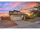 Charming two-story home featuring stucco siding, tile roof, and a two-car garage, set against a colorful sunset sky at 11965 W Monte Vista Rd, Avondale, AZ 85392