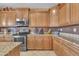 Functional kitchen featuring stainless steel appliances, mosaic backsplash, and ample wooden cabinet storage space at 11965 W Monte Vista Rd, Avondale, AZ 85392