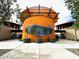 Community clubhouse entrance featuring modern architecture with a curved orange facade at 13142 E Verbina Ln, Florence, AZ 85132