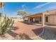 Landscaped backyard featuring a covered patio, desert landscaping, and a mature shade tree at 13208 W Desert Rock Dr, Surprise, AZ 85374