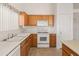 Kitchen with white appliances, tile floors, and wooden cabinets at 13208 W Desert Rock Dr, Surprise, AZ 85374