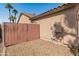 Small side yard with decorative rock, gated access, and utilities along the stucco-clad wall at 13208 W Desert Rock Dr, Surprise, AZ 85374