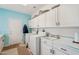 Bright laundry room with white cabinets, washer, dryer, sink, and tile floor at 14110 W Robertson Dr, Sun City West, AZ 85375