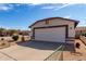 Charming home exterior with a two-car garage, desert landscaping, and a well-maintained lawn at 14957 W Bottle Tree Ave, Surprise, AZ 85374