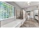 Bright bathroom featuring a soaking tub, walk-in shower, and a large glass block window for privacy at 17620 W Weatherby Dr, Surprise, AZ 85374