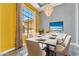 A modern dining room featuring a large window for natural light, a stylish chandelier, and seating for six at 17620 W Weatherby Dr, Surprise, AZ 85374