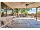 The covered patio features an outdoor seating area and a beautiful backyard with mature trees and a rock water feature at 17620 W Weatherby Dr, Surprise, AZ 85374