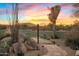 Backyard walkway featuring desert landscaping, boulders, and a vibrant sunset with views of the distant mountains at 25002 N Quail Haven Dr, Rio Verde, AZ 85263