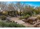 An exquisite backyard featuring lush desert plants, wooden pergola and bridge over a stream with waterfalls at 25002 N Quail Haven Dr, Rio Verde, AZ 85263