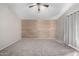 Spacious bedroom featuring neutral carpet, a wood accent wall, and a ceiling fan at 2525 E Misty Willow Ln, Phoenix, AZ 85024