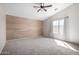 A bright bedroom featuring a wood accent wall, neutral carpet, and ample natural light at 2525 E Misty Willow Ln, Phoenix, AZ 85024