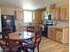 Country-style kitchen with wooden cabinets, black appliances and round wooden table with four chairs at 27575 N Dolores Pl, San Tan Valley, AZ 85144