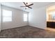 A bedroom with neutral walls, plush carpeting, ceiling fan, and ensuite bathroom at 3029 S 78Th Dr, Phoenix, AZ 85043