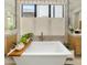 Close-up of a soaking tub with a marble countertop vanity, designer fixtures, and a neutral stone wall at 37200 N Cave Creek Rd # 1072, Scottsdale, AZ 85262