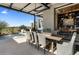 Covered outdoor dining area with a view of the pool, featuring a built-in grill, modern fan, and stylish decor at 37200 N Cave Creek Rd # 1072, Scottsdale, AZ 85262