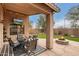 Inviting covered patio with a dining set, string lights, TV, outdoor fireplace, and well-maintained landscaping at 40656 N Key Ln, Anthem, AZ 85086