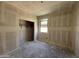 Bright bedroom shows drywall installed with closet featuring shelving and a window at 46886 W Old Timer Rd, Maricopa, AZ 85139