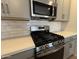 Close-up of a kitchen range featuring stainless steel appliances, quartz countertops, and modern backsplash at 46886 W Old Timer Rd, Maricopa, AZ 85139