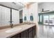 Bathroom featuring a sink with dark wood cabinets, a large mirror, and access to the backyard at 5915 E Fairfield St, Mesa, AZ 85205