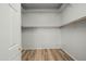 Spacious walk-in closet with white walls, wooden shelving, and wooden-look floors at 6993 S Roger Way, Chandler, AZ 85249