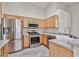 Modern kitchen with stainless steel appliances, light wood cabinets, and tile floors at 7642 W Carlota Ln, Peoria, AZ 85383