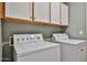 Functional laundry room featuring a washing machine, dryer, and overhead cabinets at 7642 W Carlota Ln, Peoria, AZ 85383