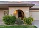 Inviting front exterior with lush flowering bushes, a charming archway, and a two-car garage at 7912 E Plaza Ave, Scottsdale, AZ 85250