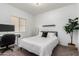 Clean-lined bedroom with a white bed, desk, and large green potted plant at 828 W Leadwood Ave, San Tan Valley, AZ 85140