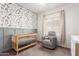 Cozy Bedroom with western-themed wallpaper, crib, and gray armchair at 828 W Leadwood Ave, San Tan Valley, AZ 85140