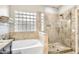 Bathroom featuring a soaking tub, shower, and decorative glass block window at 8632 E Gail Rd, Scottsdale, AZ 85260