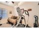 Cozy exercise room featuring an elliptical machine, comfortable daybed, and natural light from a bright window at 8632 E Gail Rd, Scottsdale, AZ 85260