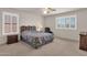 Bedroom with a large bed, ceiling fan, bright windows with white shutters, and neutral colored walls at 9019 W Acoma Dr, Peoria, AZ 85381