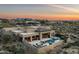 Stunning aerial view of the luxury home, pool, spa, and outdoor living spaces against a colorful desert sunset at 10238 E Rising Sun Dr, Scottsdale, AZ 85262