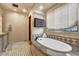 Luxurious bathroom featuring a standalone tub with marble accents and decorative tiling at 10935 E Grandview Way, Scottsdale, AZ 85255
