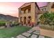 Home's exterior with an arched entry, stucco, stone details, manicured lawn, and desert views at 10935 E Grandview Way, Scottsdale, AZ 85255