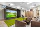 Game room with golf simulator, seating area, and wood paneled walls with athletic themed pictures at 10935 E Grandview Way, Scottsdale, AZ 85255