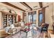 Beautiful living room with exposed wooden beams, bookshelf, and view of backyard through doors at 10935 E Grandview Way, Scottsdale, AZ 85255