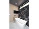 Modern bathroom featuring a standalone tub with stylish fixtures and sleek black marble accent wall at 11578 N 80Th Pl, Scottsdale, AZ 85260