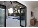 View of a modern patio with a pool and small waterfall feature through open black frame folding glass doors at 11578 N 80Th Pl, Scottsdale, AZ 85260