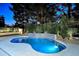 Sparkling pool with a decorative waterfall feature surrounded by mature landscaping and ambient lighting at 11578 N 80Th Pl, Scottsdale, AZ 85260