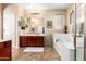 A well-lit bathroom with cherry cabinets, a soaking tub, and tile flooring at 1213 W Deoni Trl, San Tan Valley, AZ 85143