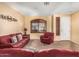 Inviting living room featuring plush red furniture, a cozy carpet, and a bright front door at 1213 W Deoni Trl, San Tan Valley, AZ 85143