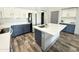 Stylish kitchen featuring white and blue cabinets, quartz countertops, a large island with a sink, and wood-look flooring at 1353 E Poncho Ln, San Tan Valley, AZ 85143