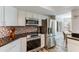 Updated kitchen with stainless steel appliances and white cabinets, plus a view into the dining room at 15056 N 43Rd St, Phoenix, AZ 85032