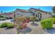 Charming single-story home featuring a desert landscape with flowering shrubs and a beige facade at 15779 W Remington Dr, Surprise, AZ 85374